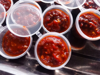 a bunch of chili paste in a plastic cup. Chili shrimp paste. food background. Sambal terasi