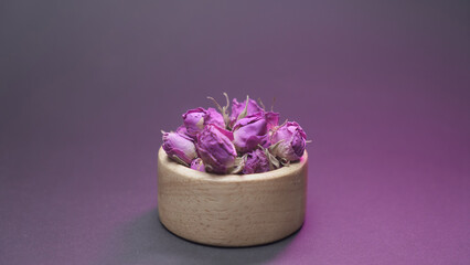 Dried damask rose buds in a small wooden bowl, food backdrop