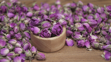 Dried damask roses in a small wooden bowl on wooden table