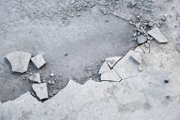 Concrete floor surface with cracks and pieces of chipped plaster