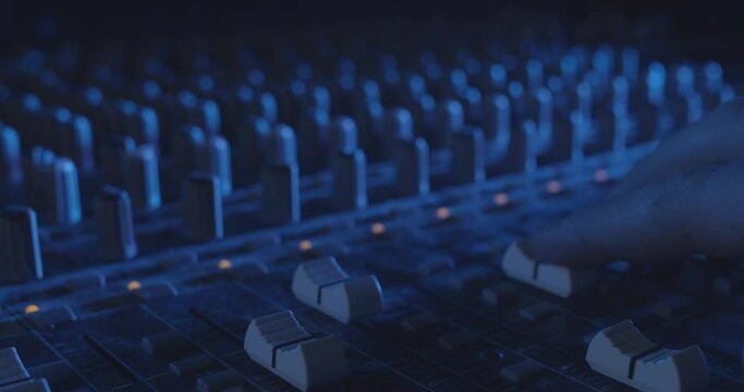 DJ Adjusting Audio Levels on Professional Console in Cinematic Atmosphere	