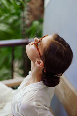Happy woman standing on a tropical balcony, enjoying a relaxing vacation in a trendy apartment She smiles, basking in the warm sunlight, embracing the freedom and joy of a peaceful morning With