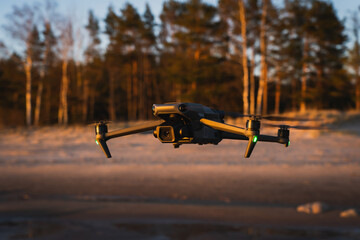 A large professional drone with a camera in flight in nature, on the seashore.