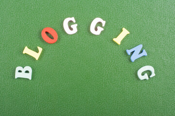 BLOGGING word on green background composed from colorful abc alphabet block wooden letters, copy...