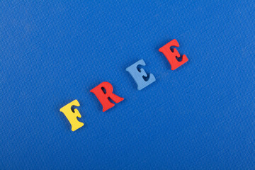 FREE word on blue background composed from colorful abc alphabet block wooden letters, copy space...