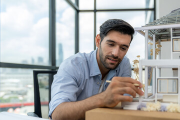 Closeup portrait of smart caucasian architect engineer inspect house model while thinking about...