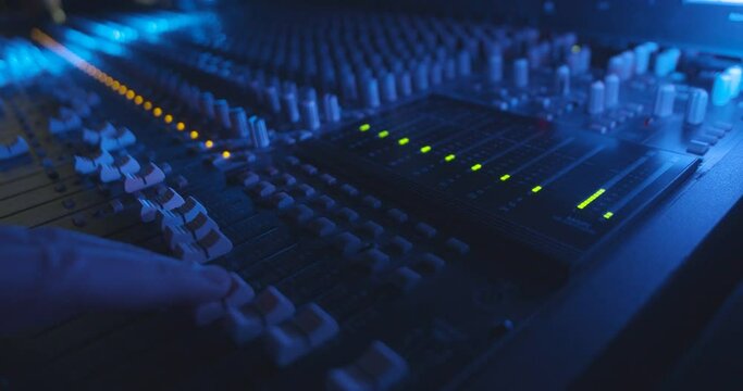 DJ Adjusting Audio Levels on Professional Console in Cinematic Atmosphere