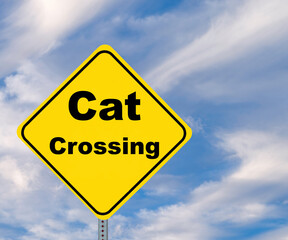 Yellow Diamond shaped warning road sign, Cat Crossing, against a cloudy blue sky with copy space.