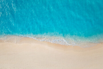 Summer seascape beautiful waves, blue sea water in sunny day. Top view from drone. Sea aerial surf, amazing tropical nature background. Mediterranean bright sea bay, waves splashing beach sandy coast