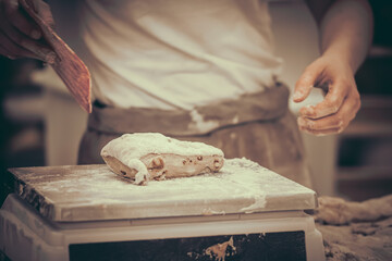 A female baker weighs pieces of dough. Traditional craft.