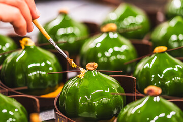 Confectioner's hands covering tartlets with an orange glaze. Preparation of the tartlets by a professional pastry chef.