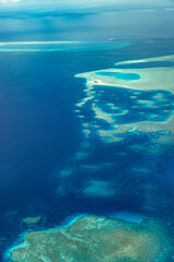 Aerial view or top view of tropical island beach with clear water coral reef. Maldives atolls, nature paradise. Shades of blue, relaxing aerial seascape, landscape. Sunny exotic travel background