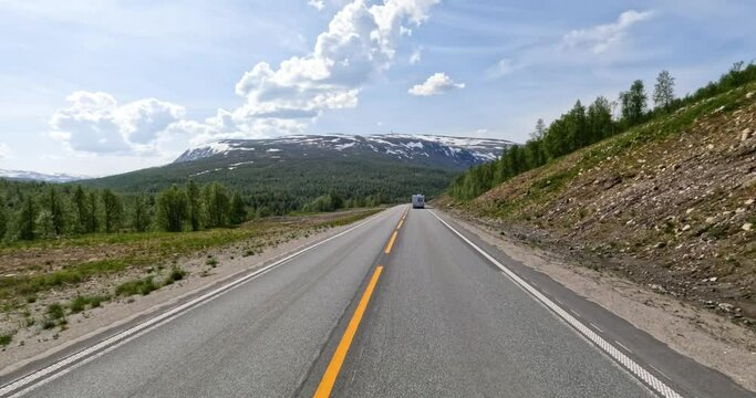 There is a motorhome travel RV with travelers on the way. Driving a Car on a Road in Norway at dawn. Point-of-view driving. Family vacation travel RV, holiday trip in motorhome, Caravan car Vacation.