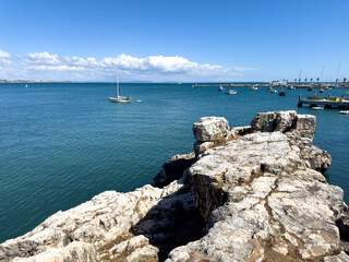 Large rock overlooking the calm Atlantic Ocean and ships in the background.