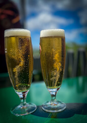 Cold beers under the sun in company. Blurred background.