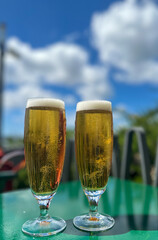 Cold beers under the sun in company. Blurred background.