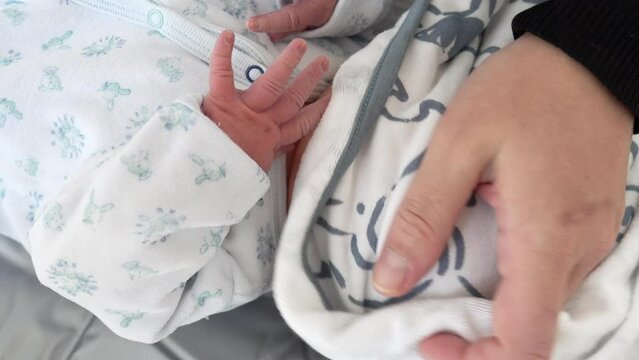Mother's hands gently drying newborn baby hair and head with towel laid after bath