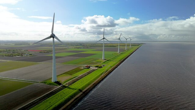 Windmill park in the Netherlands in Spring, drone aerial view of windmill turbines generating green energy electrically, row of windmill turbines on a Dutch dike by the lake Ijsselmeer