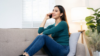 Obraz premium A woman is sitting on a couch and talking on her cell phone