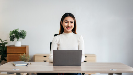 A woman is sitting at a desk with a laptop in front of her
