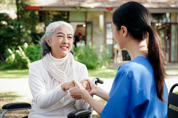 Obraz premium A woman in a blue shirt is helping an elderly woman in a wheelchair