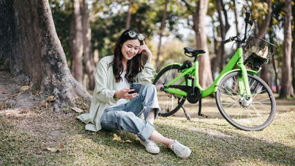 A woman is sitting on the grass next to a green bicycle