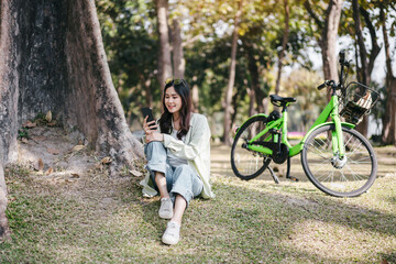 A woman is sitting on the grass next to a green bicycle