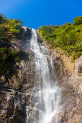A waterfall flowing in a rocky area. The cascading water creates a beautiful natural landscape in a mountainous setting. The rushing water adds to the serene outdoor environment. Sikkim, India