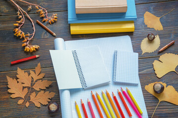 Autumn, back to school. Books, colored pencils,  open notebooks and dry yellow leaves on rustic...