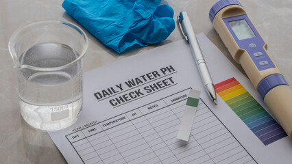 daily water ph check list on the table . Glove , pen , ph checker and beker with water on the table. Water quality tester on the table  © hunterpic2013