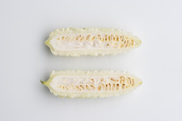 Top view of the cross sections of a fresh white bitter melon, cut in halves, isolated on white....