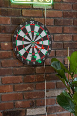 Dart board with darts on a brick wall.