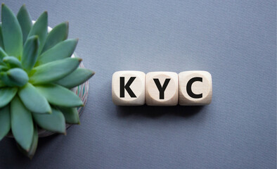 KYC - Know Your Customer. Wooden cubes with word KYC. Beautiful grey background with succulent...