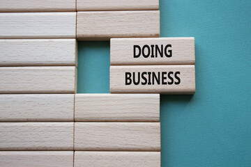Doing Business symbol. Concept word Doing Business on wooden blocks. Beautiful grey green background. Business and Doing Business concept. Copy space