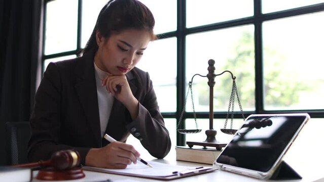 Serious female lawyer working on paperwork in law office, she is reading and signing contract agreement.