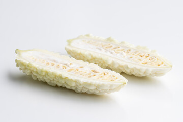 Closeup of the cross sections of a fresh white bitter melon, cut in halves, isolated on white....
