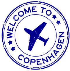 Grunge blue welcome to copenhagen word with plane icon round rubber seal stamp on white background