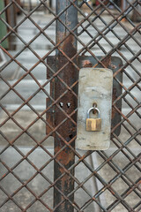 padlock hanging on a rusted steel gate