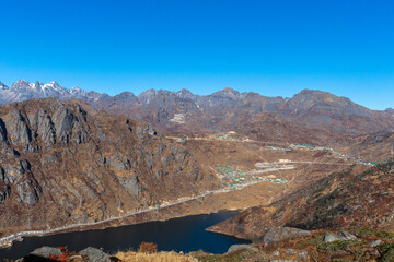 In the Himalayas, a lake winds through a canyon surrounded by towering mountains. The rugged terrain, clear sky, and pristine water create a breathtaking natural landscape in this highland region.