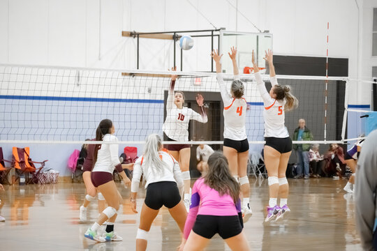 Female college volleyball player rolls the ball over the block