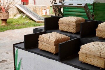 Indonesian styled rattan bamboo anyaman bambu organic eco friendly square box storage handmade crafts isolated on horizontal ratio black sectioned table and outdoor grasss background.