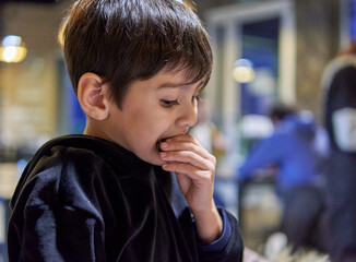portrait of latin boy eating a cookie for breakfast in an argentinian bar. selective focus