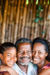 Fototapeta premium Afro-American family, father, mother and daughter hug and smile looking at the camera. Concept of family, diversity and ethnicity.