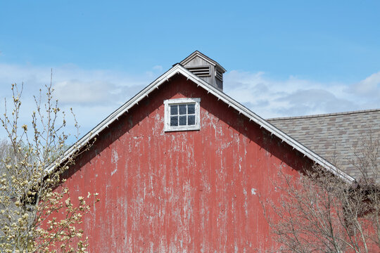 An old red barn with a window and blue sky above.
