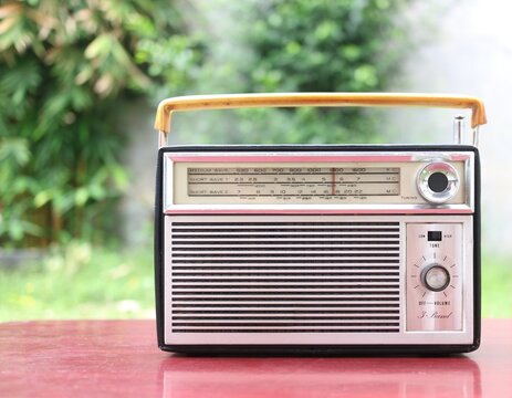 vintage silver transistor radio on wooden table backyard background