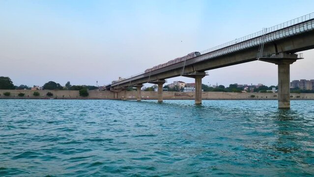 Metro rail train locomotive crossing over the blue waters of a river on an overhead bridge showing the infrastructure development in Gujarat, Ahmedabad, India