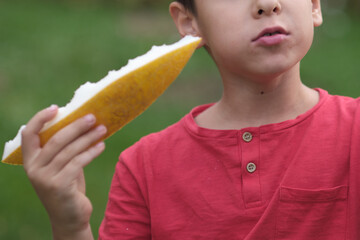Close focus on a boy enjoying a melon, his fingers gently pressing the fruit. Celebrates the...