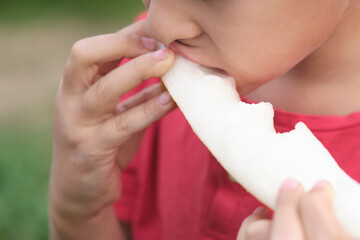 Detailed shot capturing a child's delight in biting into a juicy melon, highlighting the textures...