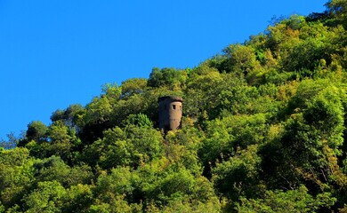 Fototapeta na wymiar An ancient observation tower on a mountainside overgrown with dense vegetation in Montenegro