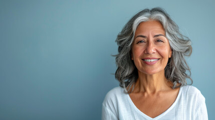 A woman with gray hair is smiling and wearing a white shirt - Powered by Adobe